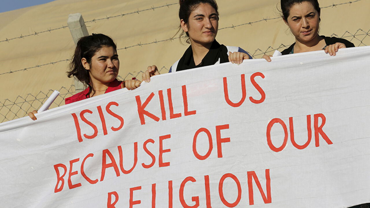 MIDEAST-CRISIS/REFUGEES Yazidi refugee women stand behind a banner as they wait for the arrival of United Nations High Commissioner for Refugees Special Envoy Angelina Jolie at a Syrian and Iraqi refugee camp in the southern Turkish town of Midyat in Mardin province, Turkey, June 20, 2015. REUTERS/Umit Bektas - RTX1HE42