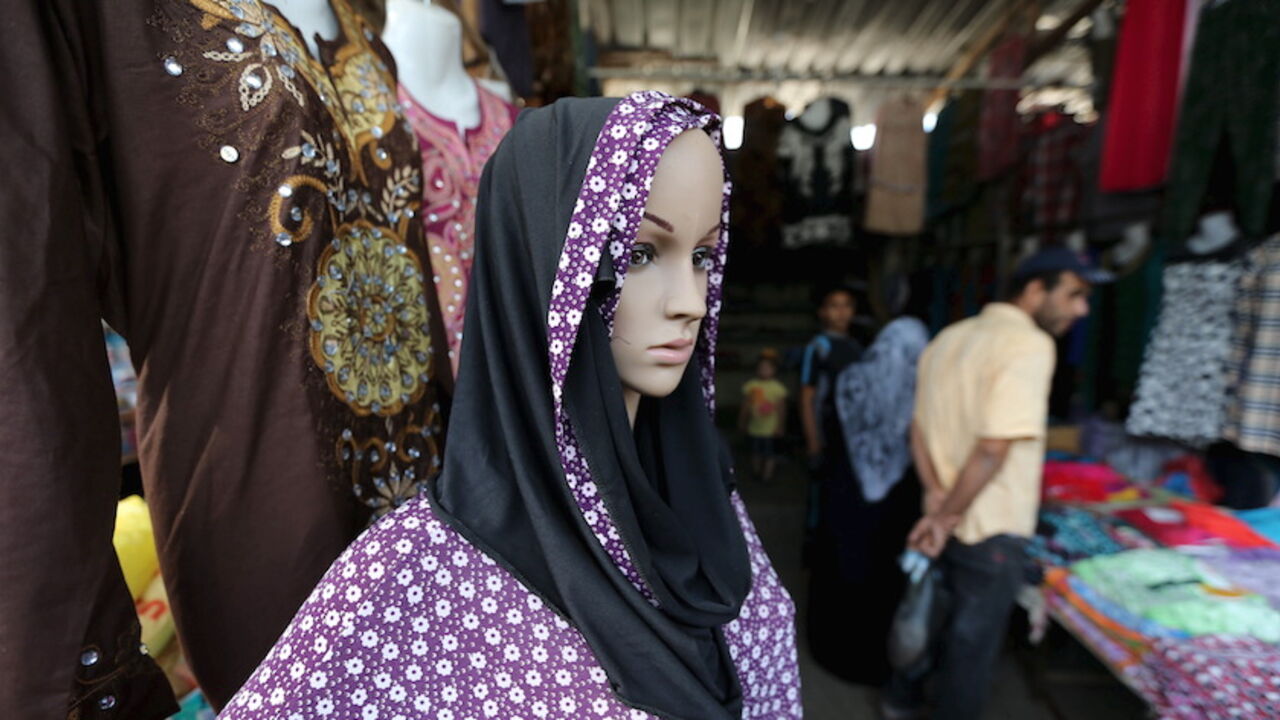 PALESTINIANS-RELIGION/ Palestinians shop as a mannequin displaying a headscarf and robe is seen at a market ahead of the Eid al-Adha festival in Khan Younis in the southern Gaza Strip September 23, 2015. Muslims across the world are preparing to celebrate the annual festival of Eid al-Adha or the Feast of the Sacrifice, which marks the end of the annual haj pilgrimage, by slaughtering goats, sheep, cows and camels in commemoration of the Prophet Abraham's readiness to sacrifice his son to show obedience to Allah. REUTERS/Ibraheem