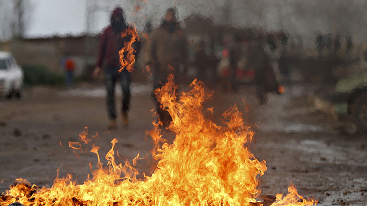 Palestinians are seen behind flame from burning tyres during clashes with Israeli troops in the West Bank town of Qabatya, near Jenin February 22, 2016. Israeli forces closed the main entrance of the town on Monday a day after a Palestinian from Qabatya was shot dead by Israeli troops after he tried to stab a soldier, Palestinian witnesses said. REUTERS/Mohamad Torokman - RTX2829U