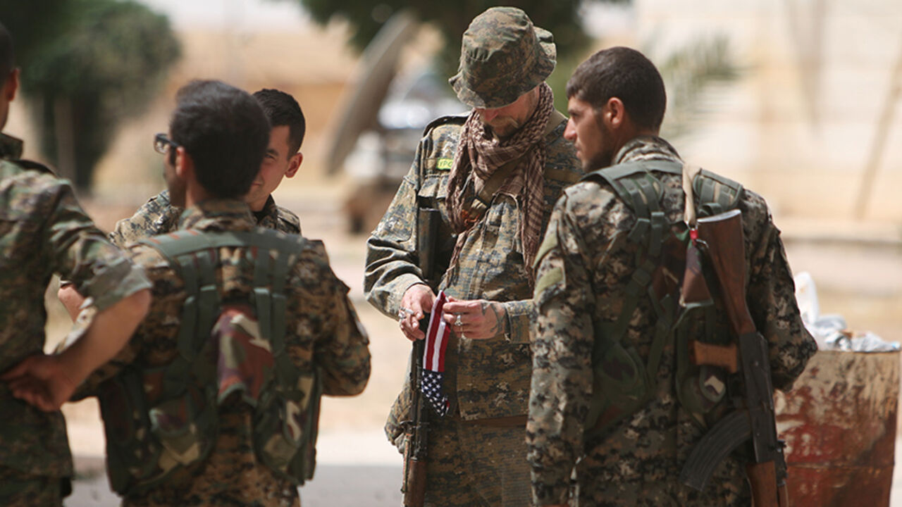 MIDEAST-CRISIS/SYRIA-RAQQA A U.S. fighter, who is fighting alongside with Syria Democratic Forces (SDF), carries his national flag as he stands with SDF fighters in northern province of Raqqa, Syria May 27, 2016. REUTERS/Rodi Said - RTX2EIZN
