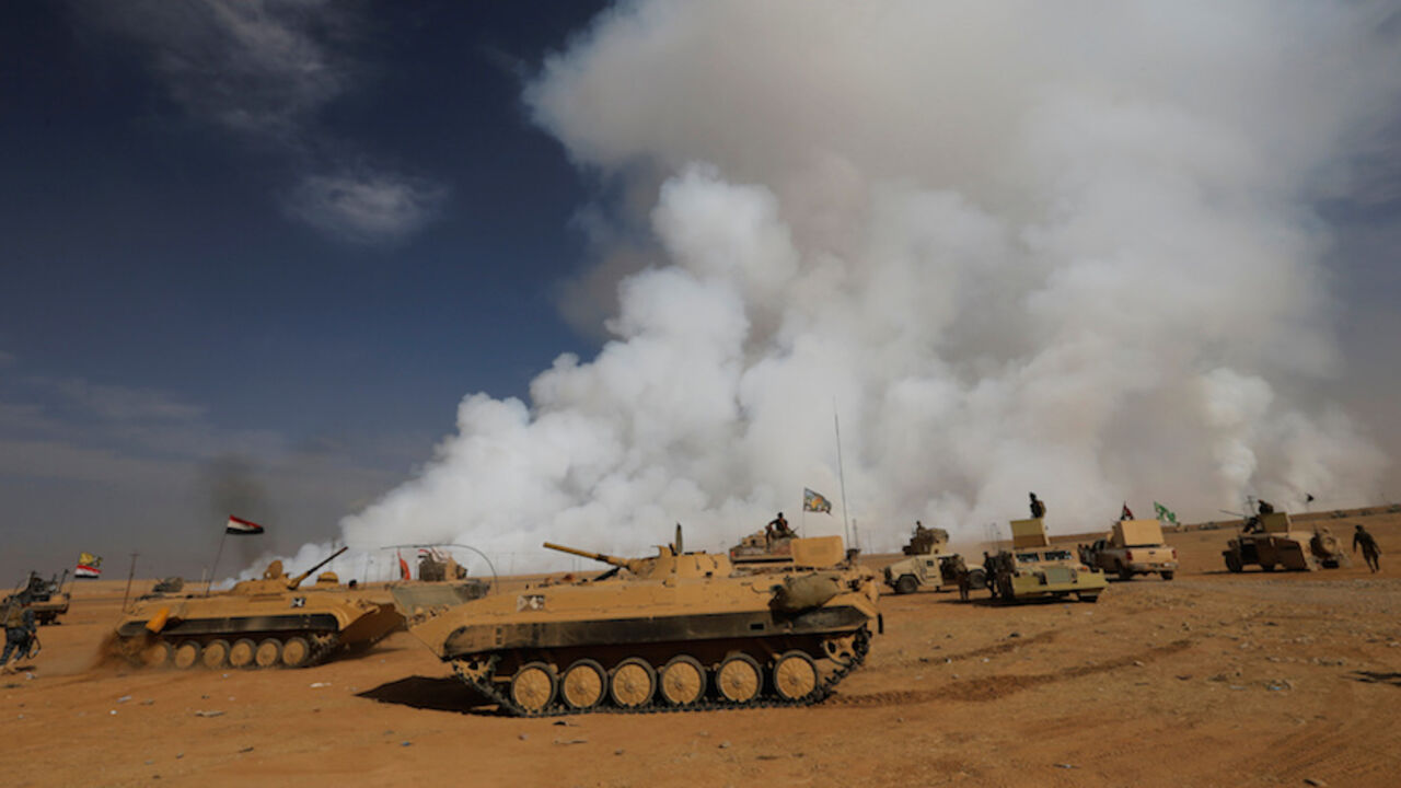 MIDEAST-CRISIS/IRAQ-MOSUL REFILE - ADDITIONAL CAPTION INFORMATIONIraqi army gather after the liberation of a village from Islamic State militants, south of Mosul, during an operation to attack Islamic State militants in Mosul, Iraq, October 21, 2016, as toxic smoke is seen over the area after Islamic State militants set fire to a sulphur factory. REUTERS/Thaier Al-Sudan TPX IMAGES OF THE DAY - RTX2PXNT