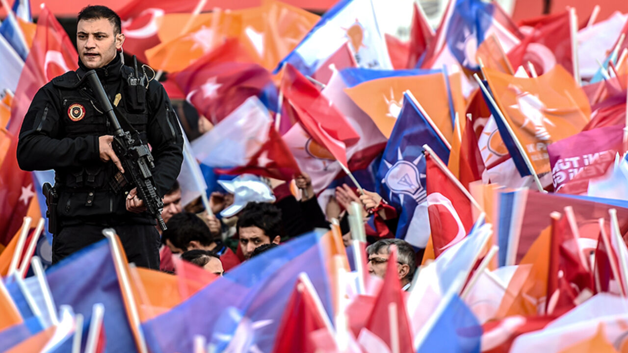Par8311759 A security stand guard while supporters wawe Turkish national and AKP party flags during a mass campaign rally of ruling Justice and Development Party (AKP) on October 25, 2015 at Yenikapi in Istanbul, a week ahead of the country's general elections on November 1. AFP PHOTO/OZAN KOSE (Photo credit should read OZAN KOSE/AFP/Getty Images)