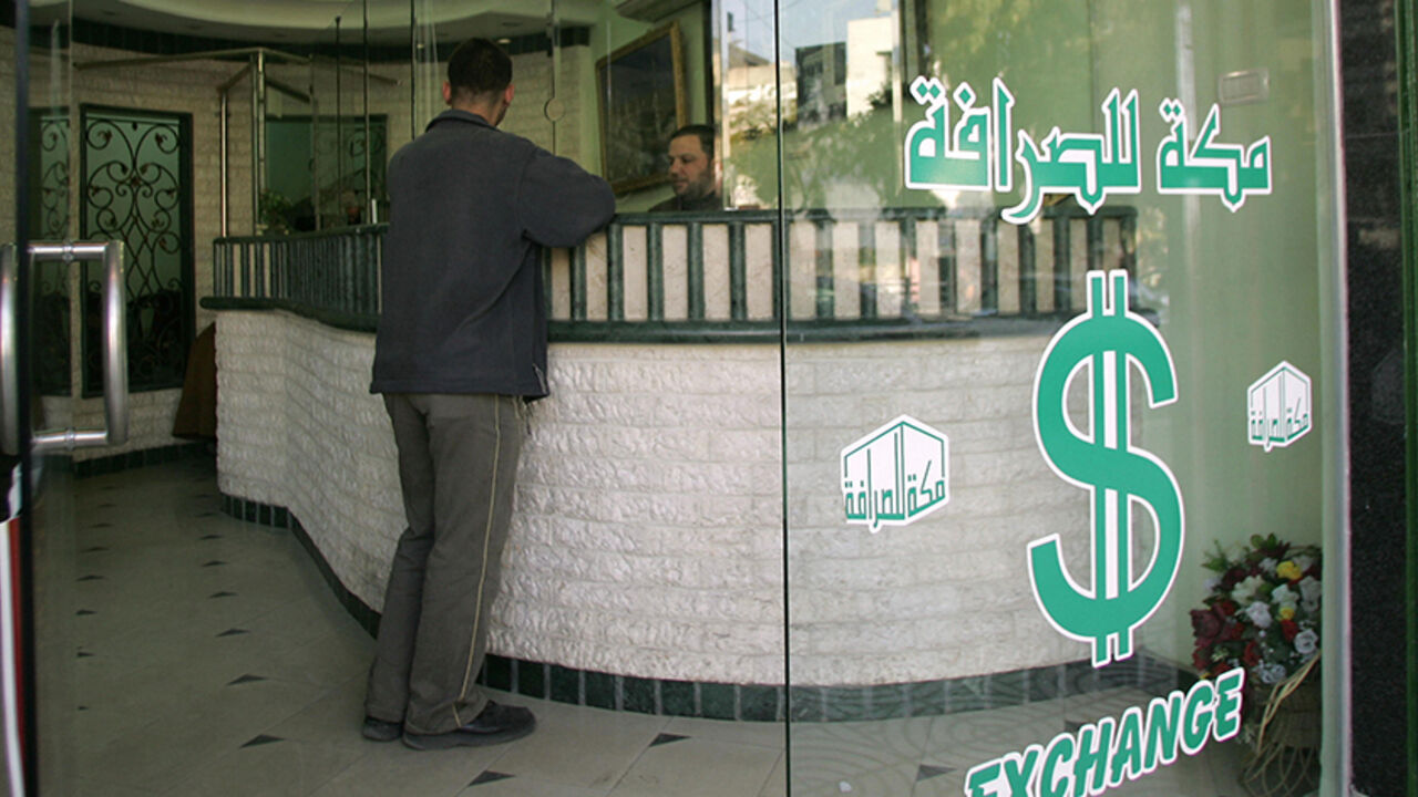 Nic24567 GAZA CITY, -: A Palestinian man changes money at a currency exchange bureau in Gaza City 30 January 2006. Hamas today sought to reassure investors in the Palestinian economy that their stocks would be safe under the Muslim fundamentalist group after it shot to power in last week's general election. AFP PHOTO/MAHMUD HAMS (Photo credit should read MAHMUD HAMS/AFP/Getty Images)