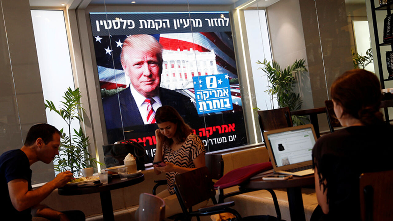 USA-ELECTION/ISRAEL People dine at a coffee shop as an image of newly elected U.S. President Donald Trump is displayed on a monitor in Tel Aviv, Israel November 9, 2016. REUTERS/Baz Ratner - RTX2SSC5