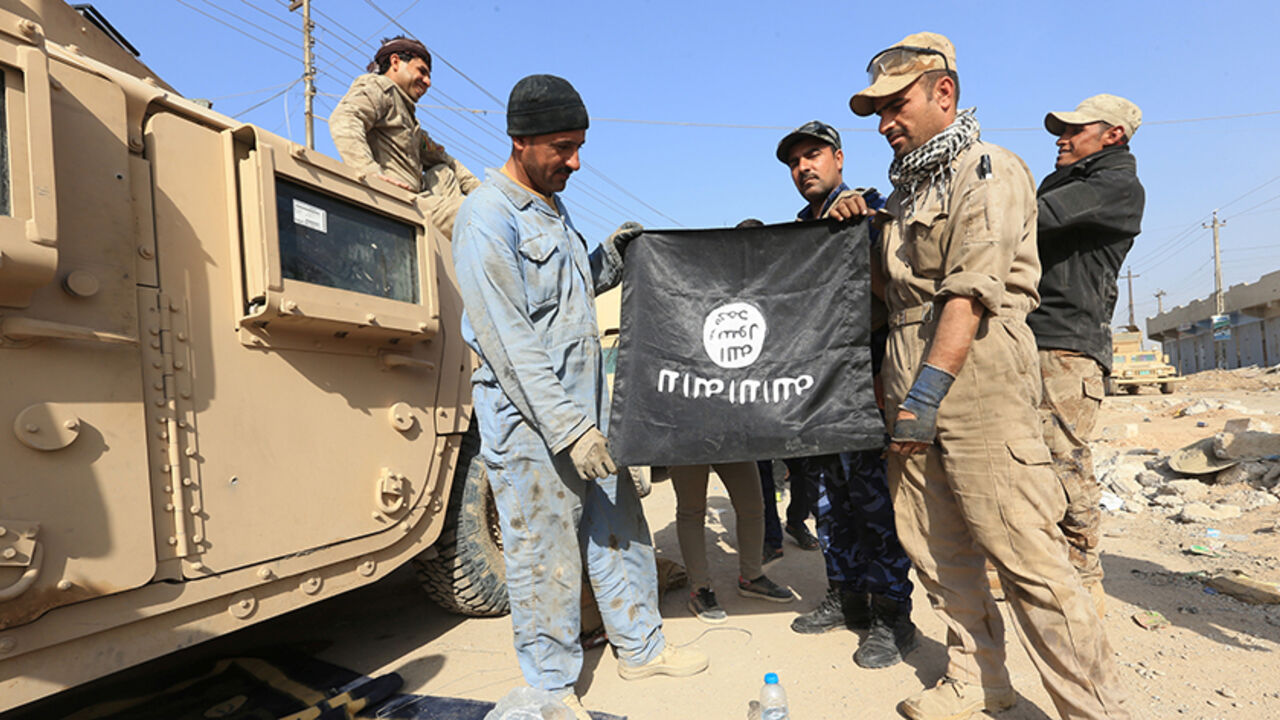 MIDEAST-CRISIS/IRAQ-MOSUL Iraqi soldiers pose with the Islamic State flag along a street in the Intisar district of eastern Mosul, Iraq, November 14, 2016, after capturing the same area from this district from the Islamic State on November 3. REUTERS/Air Jalal - RTX2TL72