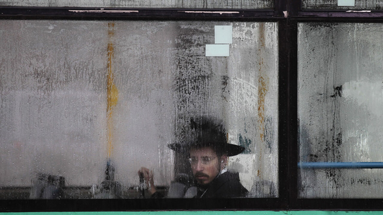 ISRAEL/ An ultra-Orthodox Jewish man looks out from a condensation-covered window of a bus in Jerusalem December 11, 2013. High winds and heavy rain showers poured across Israel on Wednesday with local media reporting by mid-morning 45 mm of rain in a central town near Tel Aviv, and snow had covered Mount Hermon near Israel's border with Syria. REUTERS/Ammar Awad (JERUSALEM - Tags: ENVIRONMENT SOCIETY TPX IMAGES OF THE DAY) - RTX16DZI