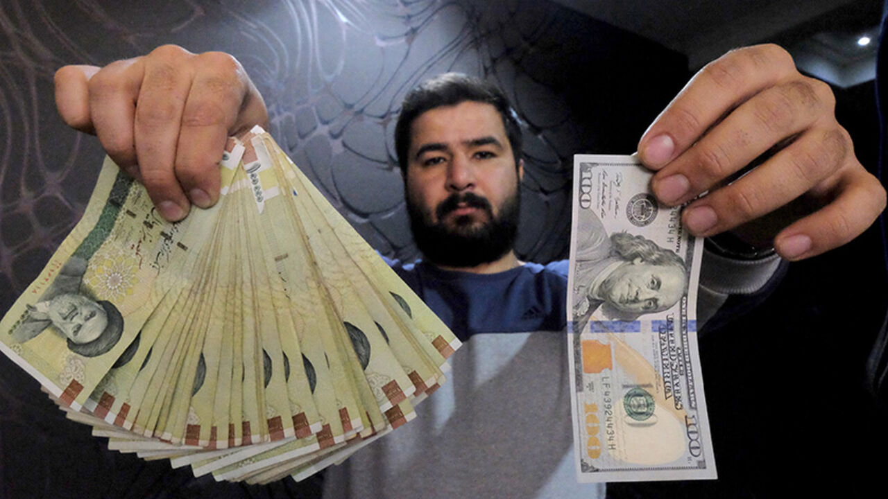 IRAN-NUCLEAR/INVESTMENT A money changer poses for the camera with a U.S hundred dollar bill (R) and the amount being given when converting it into Iranian rials (L), at a currency exchange shop in Tehran's business district, Iran, January 20, 2016. REUTERS/Raheb Homavandi/TIMA ATTENTION EDITORS - THIS IMAGE WAS PROVIDED BY A THIRD PARTY. FOR EDITORIAL USE ONLY. - RTX238AV