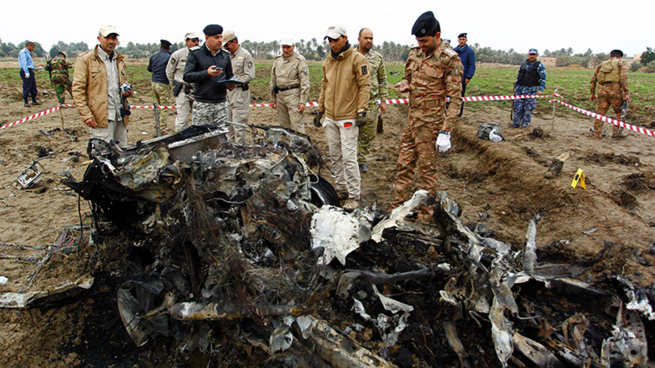 Iraqi security forces stand next to burnt car at the site of an attack on a police checkpoint, near the town of Qadisiyah, 40km south of the Iraqi holy Shiite city of Najaf on January 1, 2017.
Gunmen wearing suicide vests and driving an explosives-laden vehicle opened fire on the checkpoint near the town of Qadisiyah, which lies around 180 kilometres (110 miles) south of Baghdad. / AFP / Haidar HAMDANI        (Photo credit should read HAIDAR HAMDANI/AFP/Getty Images)