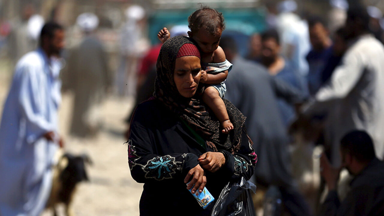 EGYPT-EID/ A woman carrying her infant son sells napkins at an old cattle market named "Al Emam Market" ahead of the Muslim sacrificial festival Eid al-Adha in Cairo, Egypt, September 19, 2015. Muslims across the world are preparing to celebrate the annual festival of Eid al-Adha or the Festival of Sacrifice, which marks the end of the annual haj pilgrimage, by slaughtering goats, sheep, cows and camels in commemoration of the Prophet Abraham's readiness to sacrifice his son to show obedience to Allah. REUTERS/Amr Abd