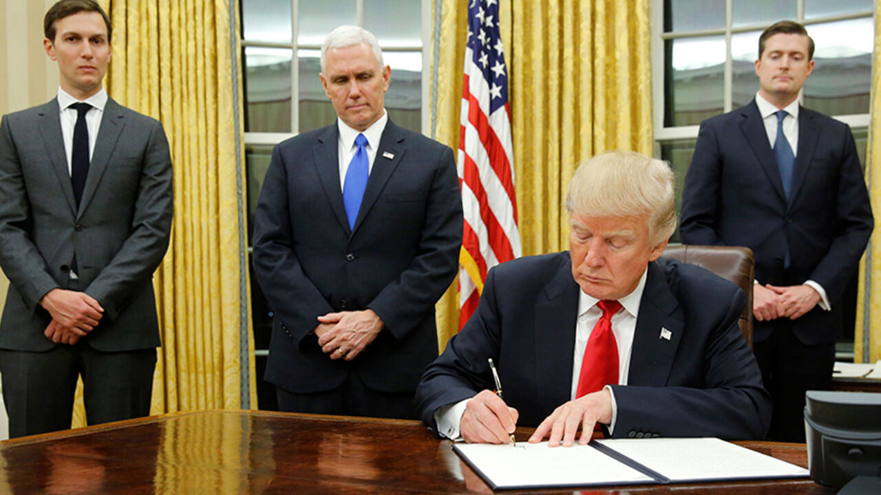 USA-TRUMP/ U.S. President Donald Trump, flanked by Senior Advisor Jared Kushner (standing, L-R), Vice President Mike Pence and Staff Secretary Rob Porter welcomes reporters into the Oval Office for him to sign his first executive orders at the White House in Washington, U.S. January 20, 2017. REUTERS/Jonathan Ernst TPX IMAGES OF THE DAY - RTSWLVK