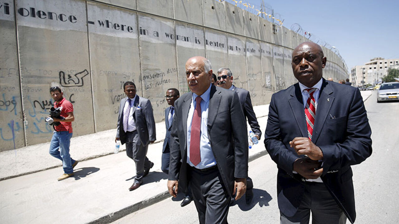 SOCCER-FIFA/PALESTINIANS Head of the Palestinian Football Association Jibril Rajoub (2nd R) walks with anti-apartheid activist Tokyo Sexwale (R) past Israel's controversial barrier as they arrive for a news conference in the West Bank town of Al-Ram, near Jerusalem, May 7, 2015. Rajoub reinforced his call for Israel to be suspended from FIFA on Thursday, saying the Israeli Football Association was part of an "apartheid, racist government" that was damaging Palestinian soccer. REUTERS/Mohamad Torokman - RTX1BZBF