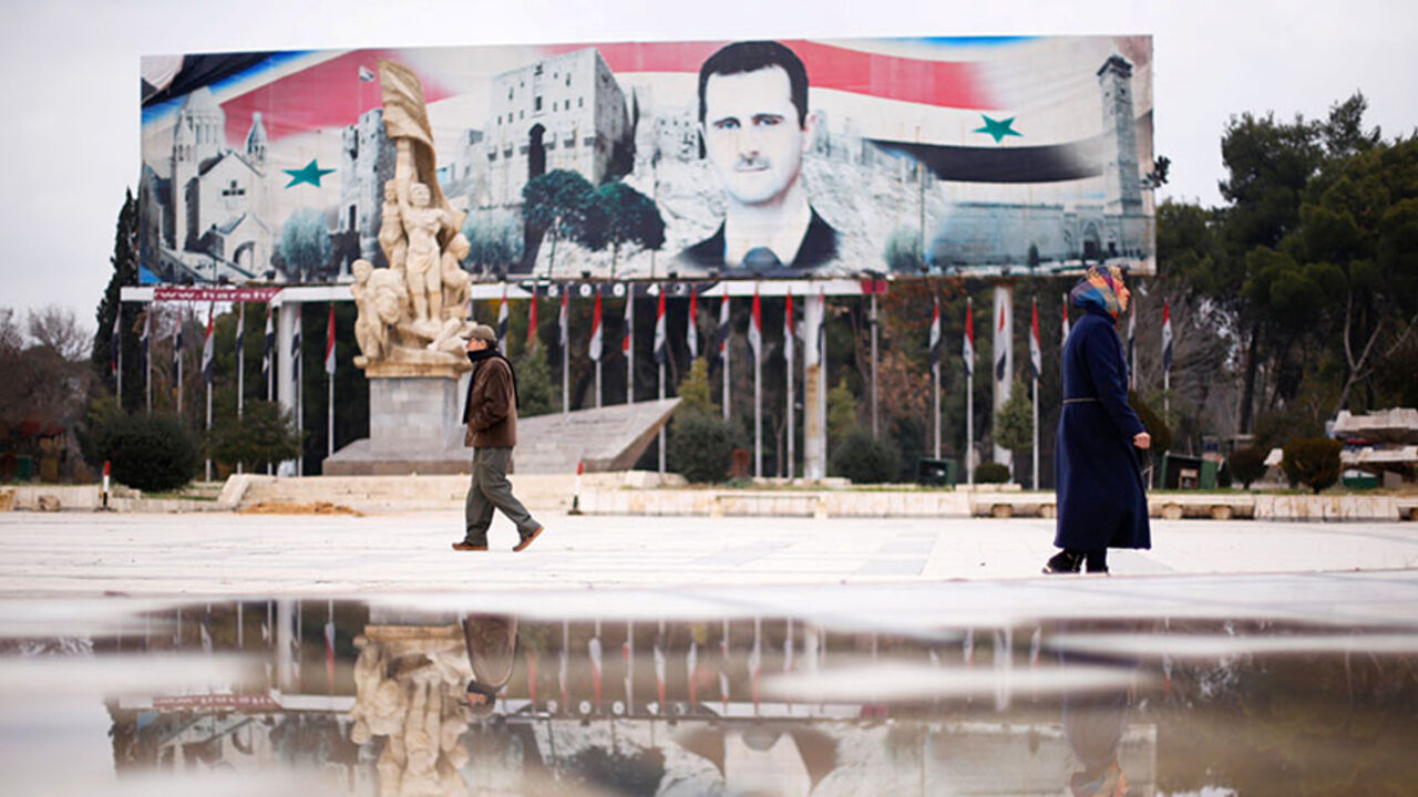 MIDEAST-CRISIS/SYRIA People walk past a billboard depicting Syria's President Bashar al-Assad at Saadallah al-Jabri Square, in the government controlled area of Aleppo, Syria December 17, 2016. REUTERS/Omar Sanadiki - RTX2VGTH