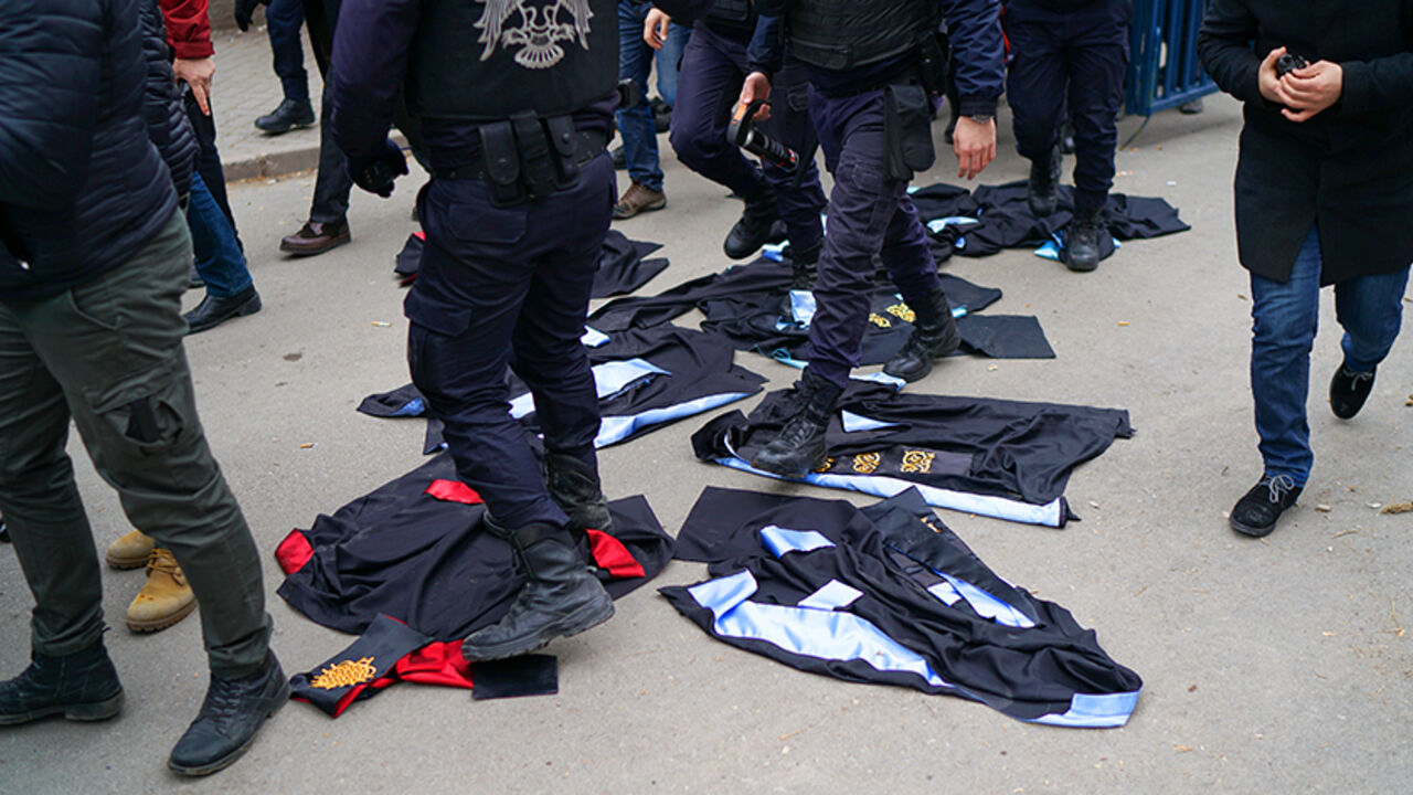 TURKEY-SECURITY/DISMISSALS Riot policemen walk over gowns which were laid down by academics during a protest against the dismissal of academics from universities following a post-coup emergency decree, in the Cebeci campus of Ankara University in Ankara, Turkey, February 10, 2017. REUTERS/Umit Bektas - RTX30F6V