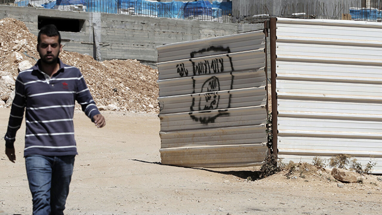 Nic6466469 A Palestinian man walks past a graffiti portraying the Islamic State (IS) group's flag in the East Jerusalem neighbourhood of Beit Hanina on July 5, 2015. AFP PHOTO / AHMAD GHARABLI (Photo credit should read AHMAD GHARABLI/AFP/Getty Images)