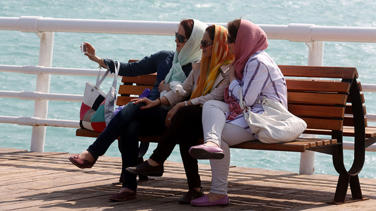 AFP_HU8IG Iranian women take a selfie on the sea front in Iran's southern resort island of Kish on November 1, 2016.
Iranian investors are pouring money into Kish island in the Gulf, hoping its white sand beaches, coral reefs and more relaxed Islamic rules, could make it a major tourism destination. / AFP / ATTA KENARE (Photo credit should read ATTA KENARE/AFP/Getty Images)