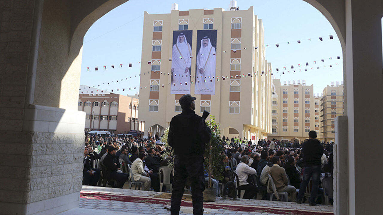 PALESTINIANS-QATAR/GAZA A member of Palestinian security forces loyal to Hamas stands guard as posters depicting Qatar's former Emir Sheikh Hamad bin Khalifa al-Thani (R) and Emir of Qatar Tamim bin Hamad al-Thani are seen on a building during the opening ceremony of Qatari-funded construction project "Hamad City", in Khan Younis in the southern Gaza Strip January 16, 2016. REUTERS/Ibraheem Abu Mustafa - RTX22NXE