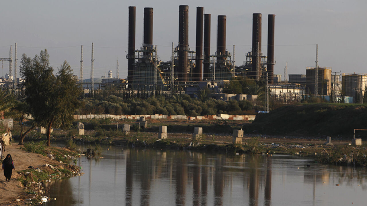 A Palestinian woman walks past Gaza's power station in the Gaza Strip March 15, 2014. The Gaza Strip's sole power station stopped generating electricity on Saturday, causing blackouts throughout the territory after it ran out of fuel, officials said. Gaza lacks much basic civil infrastructure and lives under an Egyptian-Israeli blockade meant to cut off arms flows but which also curbs imports of fuel and building supplies. REUTERS/Ibraheem Abu Mustafa (GAZA - Tags: POLITICS CIVIL UNREST ENERGY) - RTR3H86Y