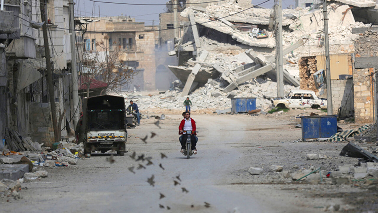 MIDEAST-CRISIS/SYRIA Birds fly near men riding a motorcycle through a damaged neighbourhood in the northern Syrian town of al-Bab, Syria March 4, 2017. REUTERS/Khalil Ashawi - RTS11G2W