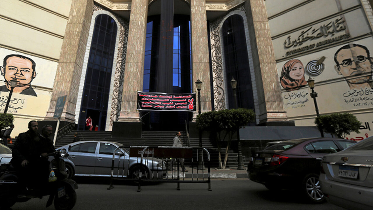 EGYPT-RIGHTS/JOURNALISTS People and vehicles move past a black sign that reads "The press; It is not a crime" in front of the Egyptian Press Syndicate's headquarters in downtown Cairo, Egypt, November 20, 2016. REUTERS/Mohamed Abd El Ghany - RTSSGRD