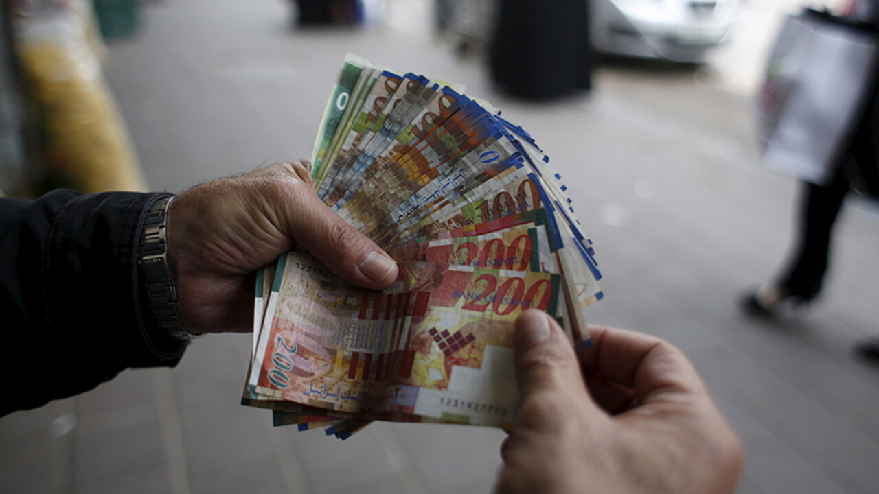 PALESTINIANS-ECONOMY/WESTBANK A Palestinian money exchanger displays money at a market in the West Bank city of Ramallah March 25, 2015. Israel's decision to withhold $130 million a month in revenue collected on behalf of the Palestinians is strangling the economy and leaving the banking system dangerously exposed, the Palestinian central bank governor said on Wednesday. REUTERS/Mohamad Torokman - RTR4UT7Y
