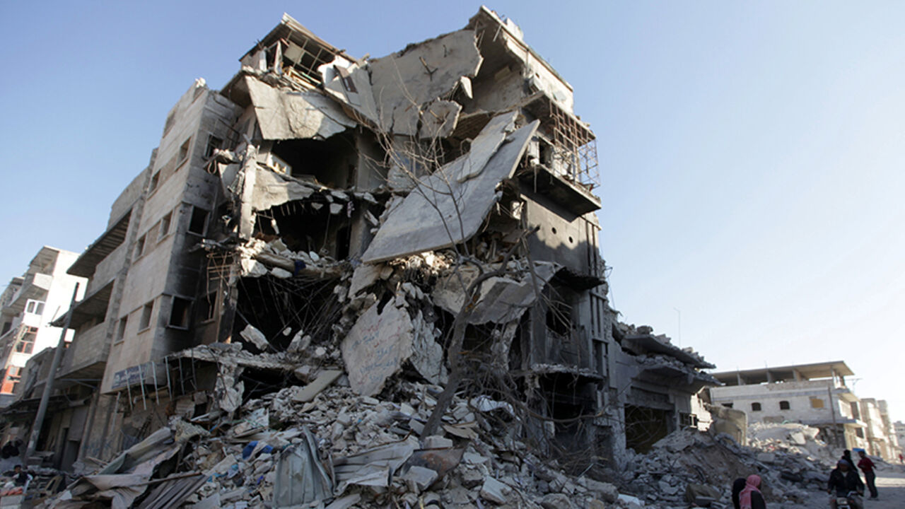 MIDEAST-CRISIS/SYRIA People stand in front of a damaged building in the northern Syrian town of al-Bab, Syria March 6, 2017. REUTERS/Khalil Ashawi - RTS11OJ8