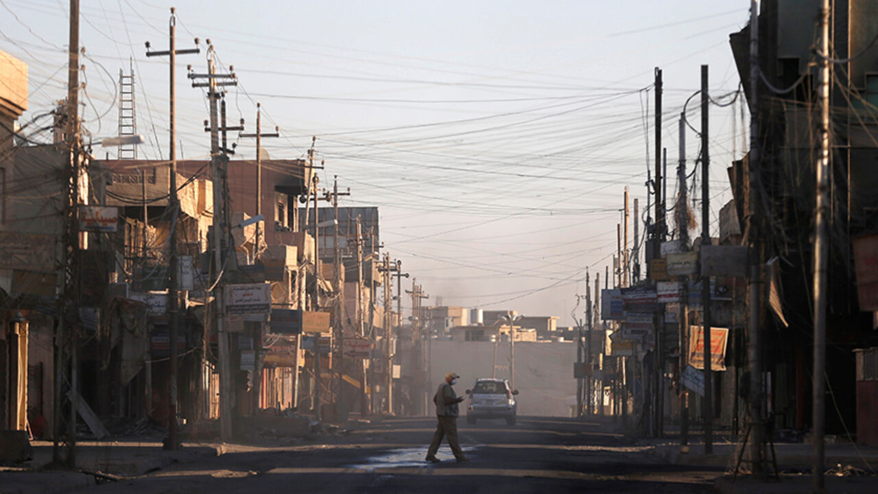 MIDEAST-CRISIS/IRAQ-CHRISTIANS A man walks across a street in Qaraqosh, east of Mosul, Iraq November 25, 2016. Picture taken November 25, 2016. REUTERS/Goran Tomasevic - RTSTT8A