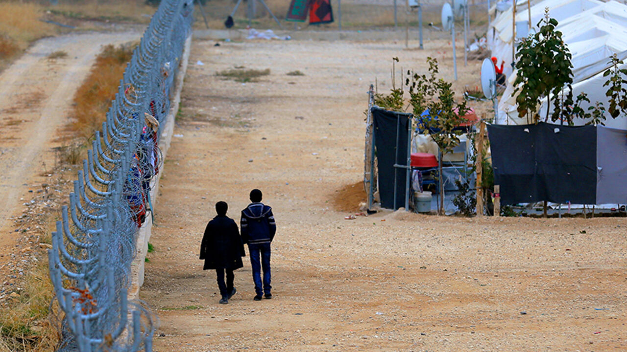 TURKEY-EUROPE/REFUGEES Two Syrian refugees walk along fences in Nizip refugee camp, near the Turkish-Syrian border in Gaziantep province, Turkey, November 30, 2016. REUTERS/Umit Bektas - RTSU1PW