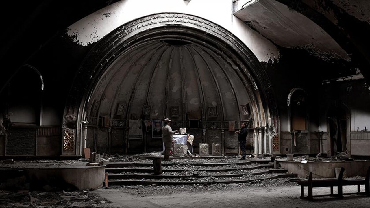 AFP_N09TJ Members of the Nineveh Plain Protection Units (NPU), a small Christian militia charged with protecting the predominantly Christian Iraqi town of Qaraqosh (Hamdaniya), pray in a destroyed church in the town which lies some 30 kilometres east of the northern city of Mosul on March 3, 2017.
Qaraqosh was ravaged by IS jihadists, who seized it in June 2014 as they rampaged across parts of northern Iraq, capturing second city Mosul and swathes of the area known as the Nineveh Plain, home to much of the county's d