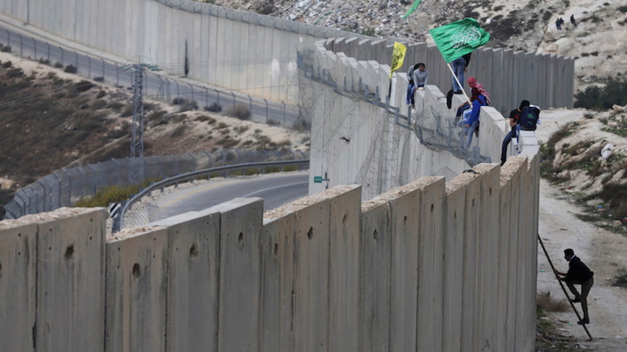 ISRAEL-PALESTINIANS/ Palestinian protesters climb over a section of the Israeli barrier that separates the West Bank town of Abu Dis from Jerusalem, during an anti-Israel protest, November 16, 2015. REUTERS/Ammar Awad - RTS7CY7