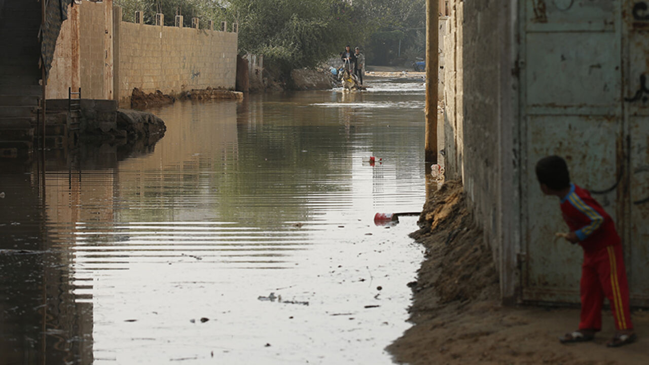 PALESTINIANS-GAZA/POWER A boy looks at Palestinians as they ride a horse cart on a street flooded with sewage water from a sewage treatment facility in Gaza City November 14, 2013. Gaza municipality said they could not operate the sewage treatment facility due to shortages in fuel and power. Gaza's lone power plant shut its generators on November 1, 2013 due to a fuel shortage, a move that will likely increase already long blackout hours in the impoverished coastal territory run by the Islamist Hamas group. Power is provided to di