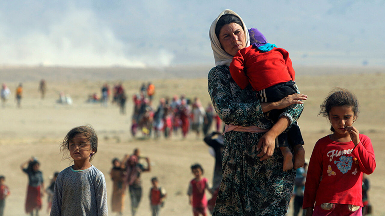 MIDEAST-CRISIS/SYRIA-YAZIDI Displaced people from the minority Yazidi sect, fleeing violence from forces loyal to the Islamic State in Sinjar town, walk towards the Syrian border on the outskirts of Sinjar mountain near the Syrian border town of Elierbeh of Al-Hasakah Governorate in this August 11, 2014. REUTERS/Rodi Said/File Photo - RTX2GIWQ