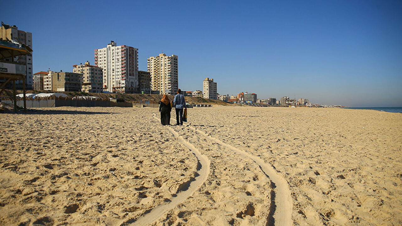 AFP_PB8SK TOPSHOT - A Palestinian couple walk along traces of cart tracks on a beach in Gaza City on June 7, 2017. / AFP PHOTO / MOHAMMED ABED (Photo credit should read MOHAMMED ABED/AFP/Getty Images)