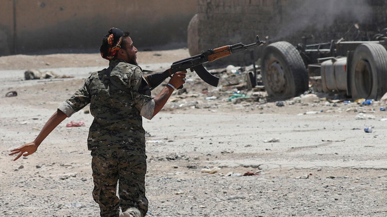 MIDEAST-CRISIS/SYRIA-RAQQA A Kurdish fighter from the People's Protection Units (YPG) fires his rifle at Islamic State militants as he runs across a street in Raqqa, Syria July 3, 2017. REUTERS/Goran Tomasevic TPX IMAGES OF THE DAY - RTS19M5W