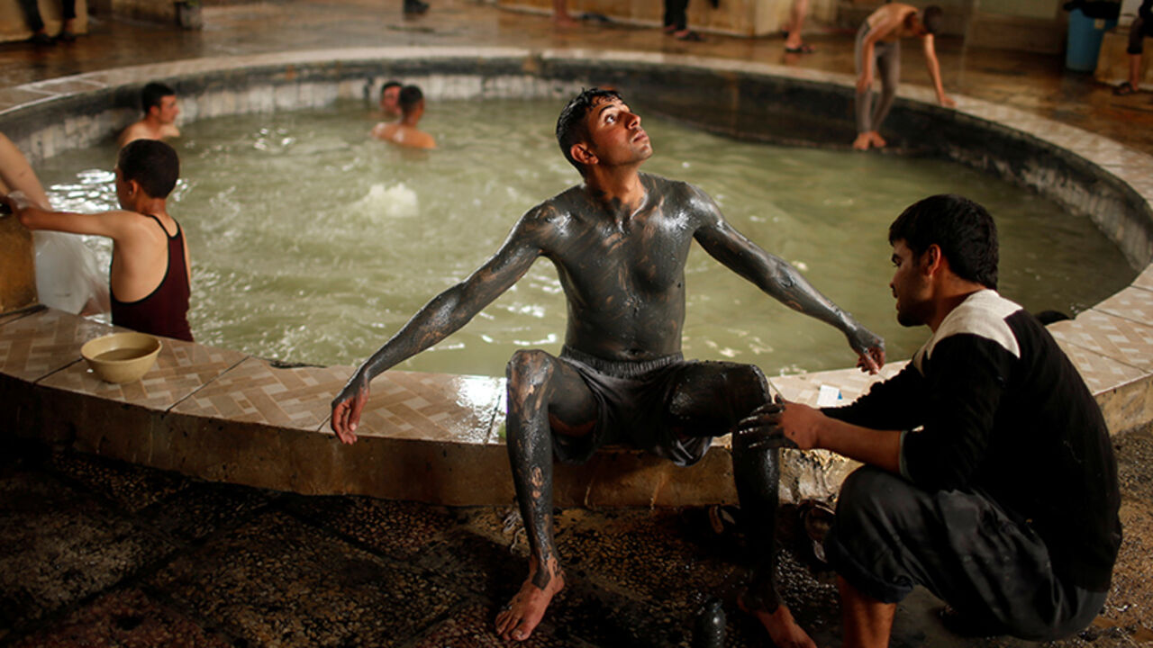 MIDEAST-CRISIS/IRAQ-SPA An Iraqi cover his boy with sand from a sulfur pond at Hammam al-Alil city south of Mosul, Iraq April 3, 2017. Picture taken April 3, 2017. REUTERS/Suhaib Salem TPX IMAGES OF THE DAY - RTX3403L
