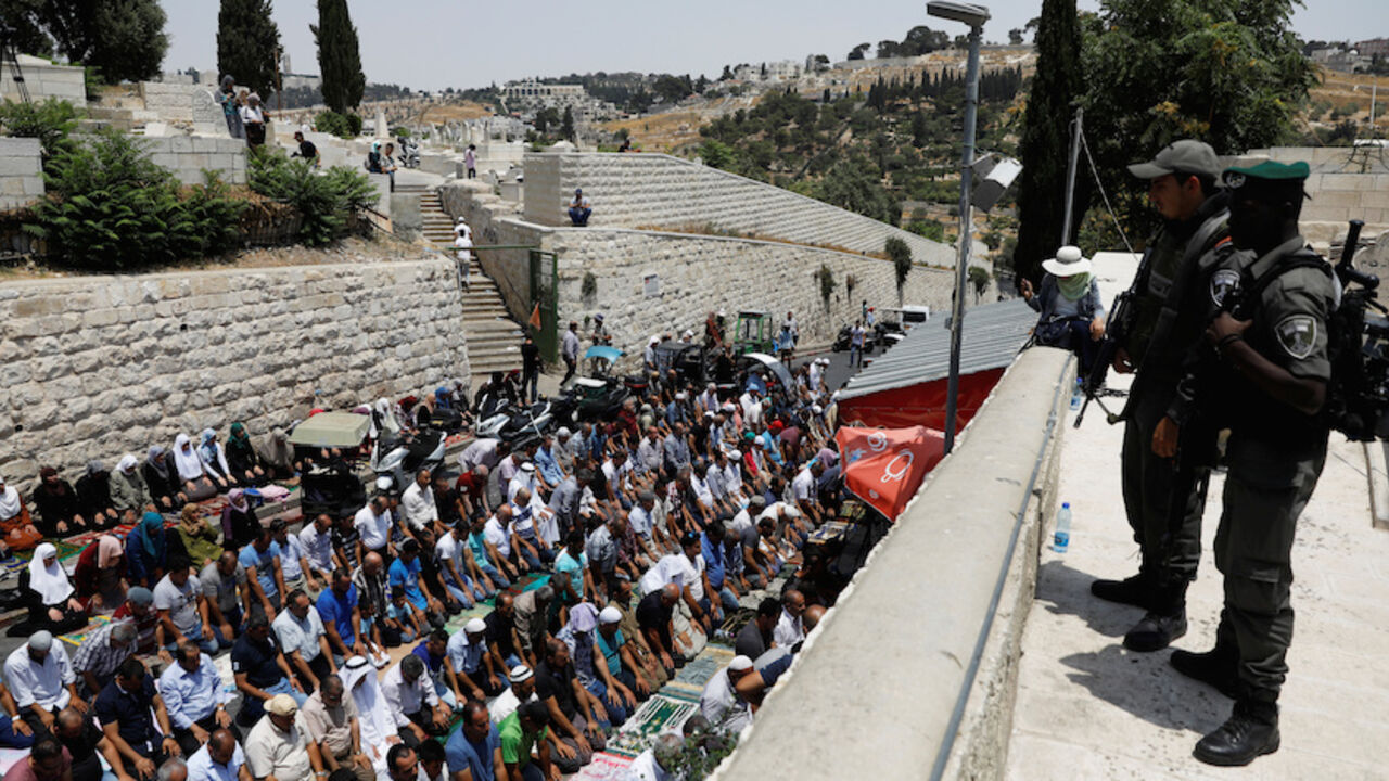 ISRAEL-PALESTINIANS/ Israeli border police officers stand guard as Palestinians pray at Lions' Gate, the entrance to Jerusalem's Old City, in protest over Israel's new security measures at the compound housing al-Aqsa mosque, known to Muslims as Noble Sanctuary and to Jews as Temple Mount July 20, 2017. REUTERS/Ronen Zvulun - RTX3C773