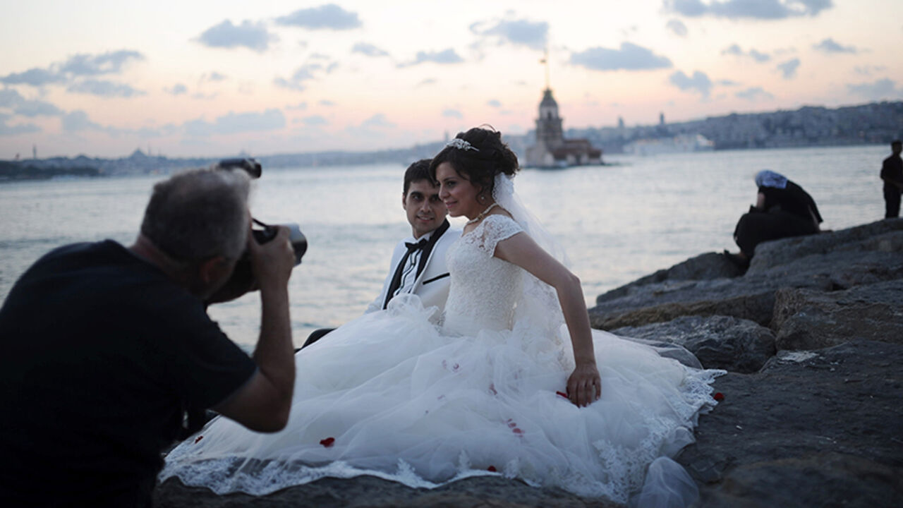 Par7638431 A newly married couple poses for their wedding pictures in front of The Maiden's Tower (background), on August 20, 2013 in Istanbul. The Maiden's Tower, also known as Leander's Tower, stands on a small islet located at the southern entrance of the Bosphorus strait 200 m (220 yd) from the coast of Usk?dar. AFP PHOTO/BULENT KILIC (Photo credit should read BULENT KILIC/AFP/Getty Images)