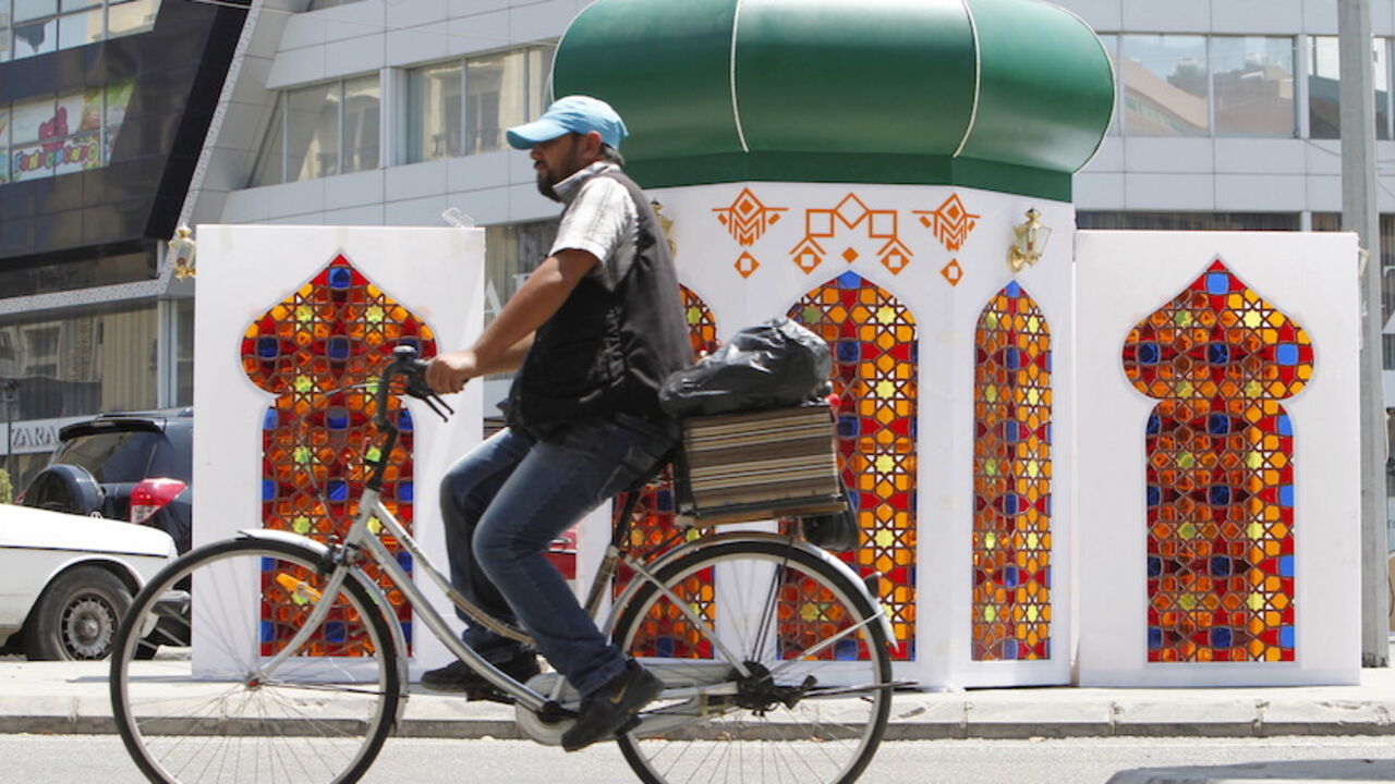 RELIGION-RAMADAN/ A man rides a bicycle near decorations erected ahead of the holy fasting month of Ramadan at the port city of Sidon, southern Lebanon, June 16, 2015. REUTERS/Ali Hashisho - RTX1GRZD