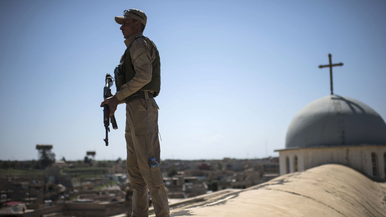 AFP_NL6F6 TOPSHOT - A Syriac Christian militiaman stands guard on top of a building during an easter ceremony at the Saint John's church (Mar Yohanna) in the nearly deserted predominantly Christian Iraqi town of Qaraqosh (also known as Hamdaniya), some 30 kilometres from Mosul, on April 16, 2017.
Qaraqosh was retaken by Iraqi forces late in 2016 as part of a massive offensive to wrest back the nearby city of Mosul from Islamic State (IS) group fighters but it remains almost completely deserted.
/ AFP PHOTO / CHRIST