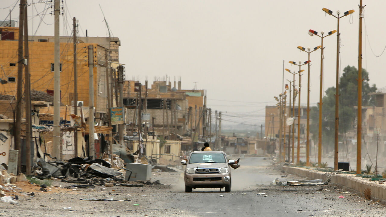 AFP_SQ3PH A car drives through a damaged street on the outskirts of Deir Ezzor on September 24, 2017, as Syrian government forces continue to press forward with Russian air cover in the offensive against Islamic State group jihadists across the province. / AFP PHOTO / STRINGER (Photo credit should read STRINGER/AFP/Getty Images)