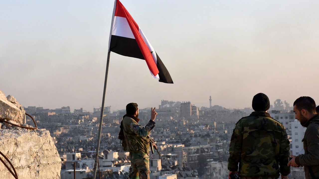 MIDEAST-CRISIS/SYRIA-ALEPPO A Syrian government soldier gestures a v-sign under the Syrian national flag near a general view of eastern Aleppo after they took control of al-Sakhour neigbourhood in Aleppo, Syria in this handout picture provided by SANA on November 28, 2016. SANA/Handout via REUTERS ATTENTION EDITORS - THIS IMAGE WAS PROVIDED BY A THIRD PARTY. EDITORIAL USE ONLY. REUTERS IS UNABLE TO INDEPENDENTLY VERIFY THIS IMAGE. - RC14B3B13650