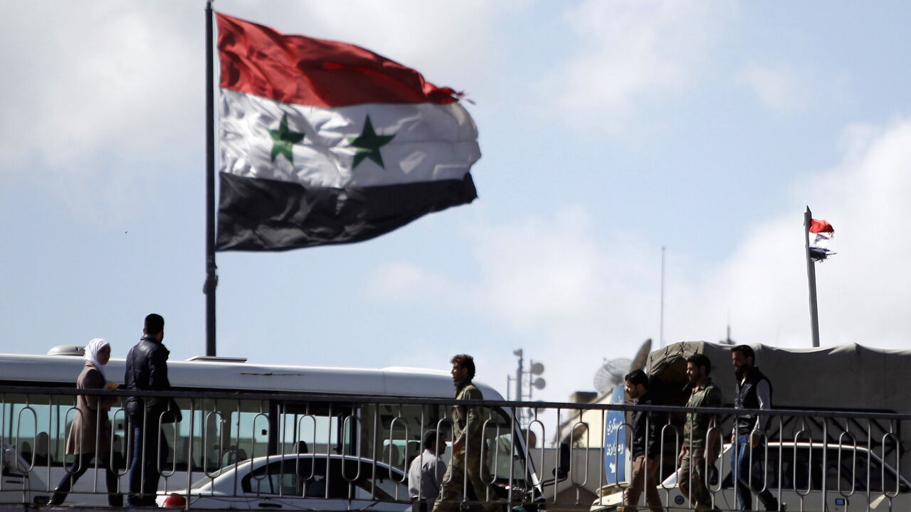 MIDEAST-CRISIS/SYRIA People walk near a Syrian national flag at the President bridge in Damascus, Syria March 14, 2016. REUTERS/Omar Sanadiki - GF10000345197