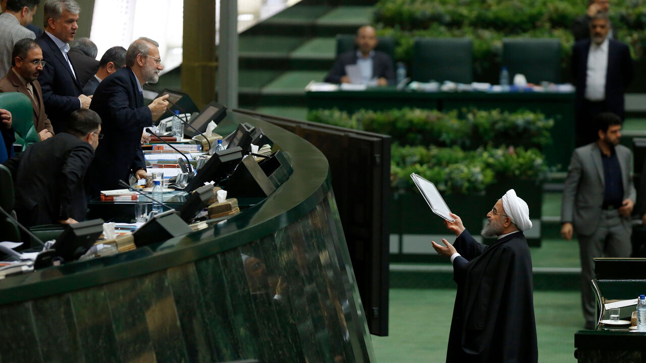 AFP_V13MU Iran's President Hassan Rouhani (R) hands out documents to Parliament Speaker Ali Larijani after presenting his budget for 2018-2019 on December 10, 2017, in Tehran. / AFP PHOTO / ATTA KENARE (Photo credit should read ATTA KENARE/AFP/Getty Images)