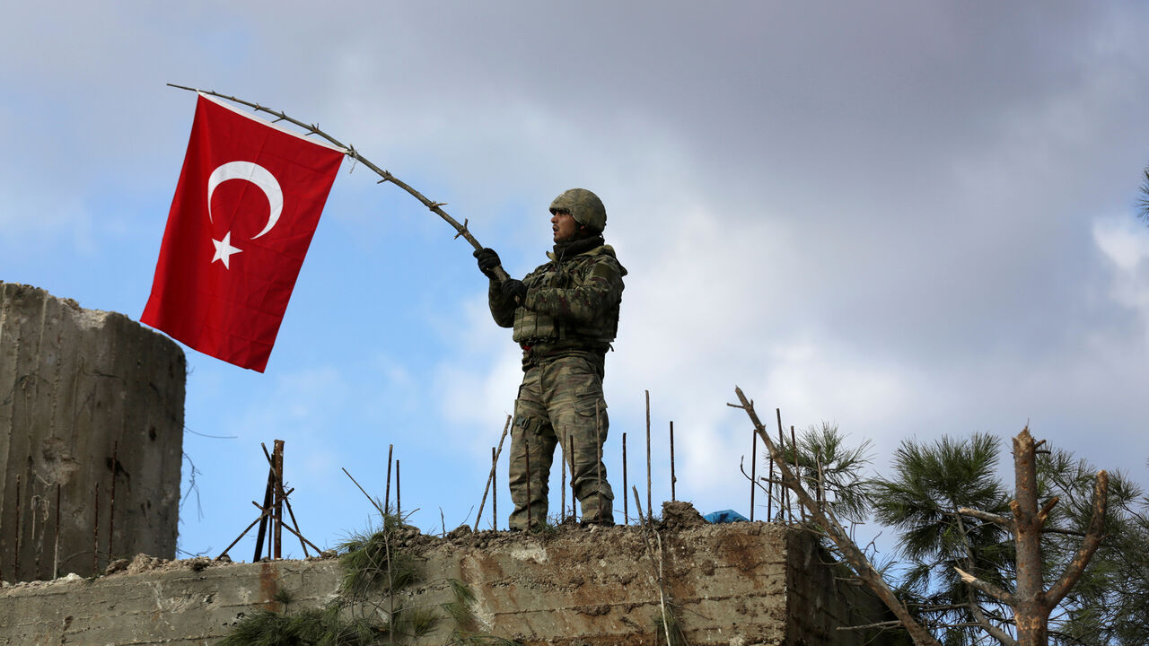 MIDEAST-CRISIS/SYRIA-TURKEY A Turkish soldier waves a flag on Mount Barsaya, northeast of Afrin, Syria January 28 ,2018. REUTERS/ Khalil Ashawi - RC13E270E570