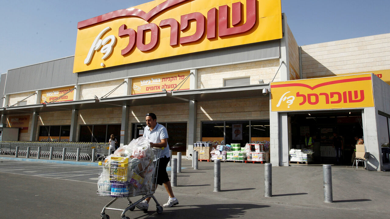 ISRAEL-TYCOONS/ A man pushes a shopping cart outside Shufersal, Israel's largest supermarket chain, in the West Bank Jewish settlement of Mishor Adumim near Jerusalem May 5, 2013. REUTERS/Ammar Awad/File Photo - S1BEUFEYLVAB