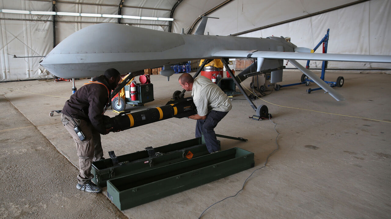 88713048 UNSPECIFIED, UNSPECIFIED - JANUARY 07: Contract workers load a Hellfire missile onto a U.S. Air Force MQ-1B Predator unmanned aerial vehicle (UAV), at a secret air base in the Persian Gulf region on January 7, 2016. The U.S. military and coalition forces use the base, located in an undisclosed location, to launch drone airstrikes against ISIL in Iraq and Syria, as well as to distribute cargo and transport troops supporting Operation Inherent Resolve. The Predators at the base are operated and maintained by