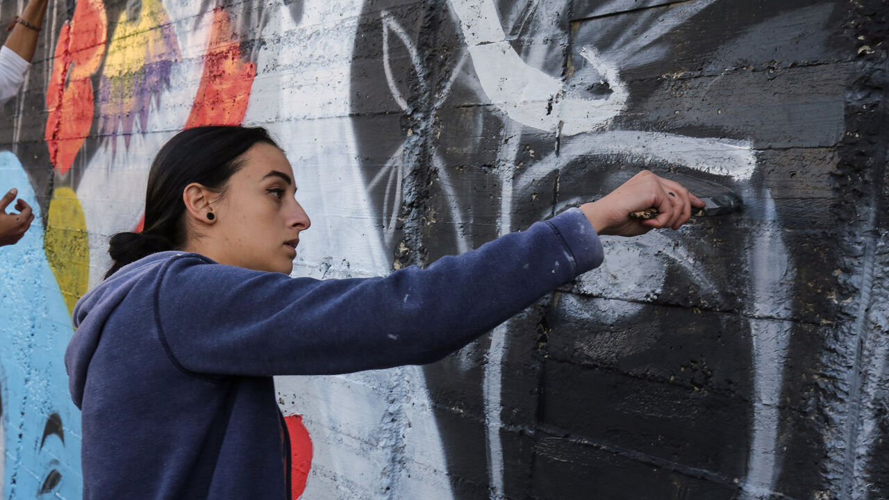 AFP_VA0F1 Suha Sultan, a 20-year-old graffiti artist and student, uses a brush to draw a mural on a wall in the Jordanian capital Amman on December 16, 2017.
A tiny group of graffiti artists are on a mission -- daubing flowers, faces and patterns across the capital Amman to bring more colour to the lives of its four million inhabitants.
In a conservative society like Jordan's, the graffiti artists have constantly had to challenge convention to carve out a niche for their works, though still with limits as they steer