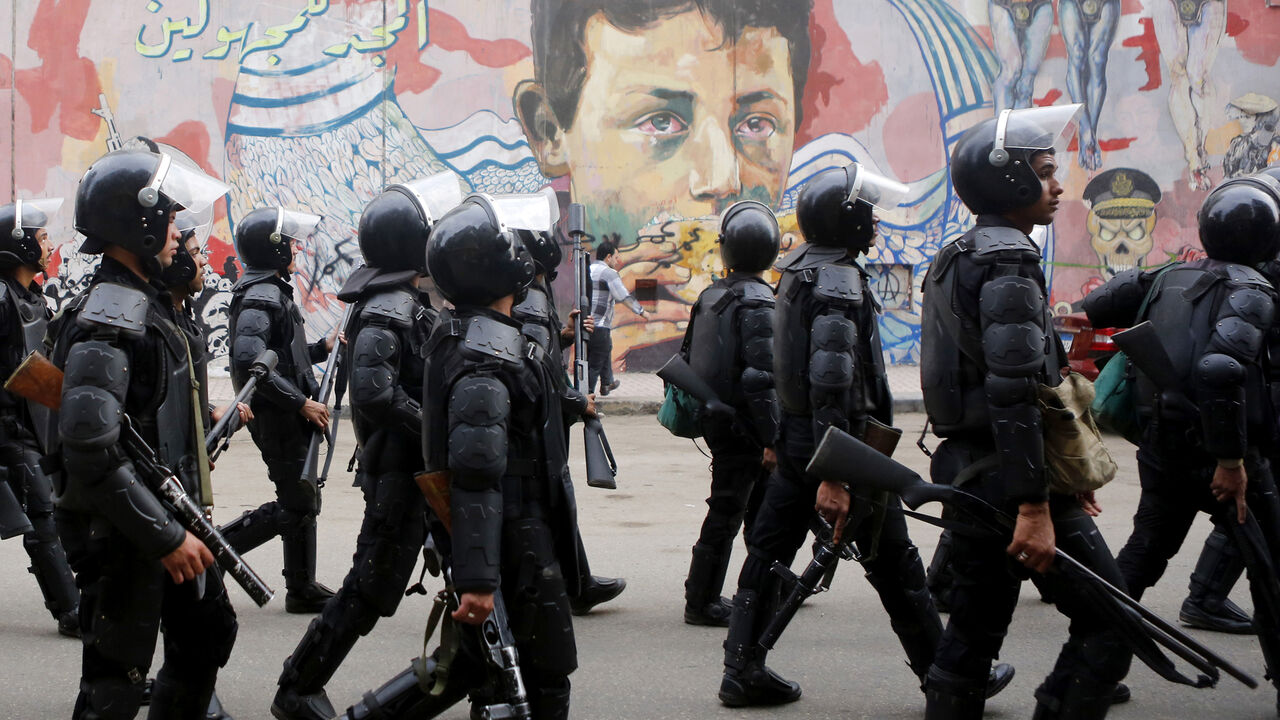 EGYPT-PROTESTS/ANNIVERSARY Riot police walk in front of graffiti representing anti-military power and Egypt's unrest, which reads "Glory to the unknown", along Mohamed Mahmoud Street during the third anniversary of violent and deadly clashes near Tahrir Square in Cairo November 19, 2014. Egyptian police arrested 25 individuals after four hundred protestors staged a march through downtown Cairo on the anniversary of deadly clashes with security forces three years ago, the interior ministry said on Wednesday. REUTERS/Amr Abdallah Dals