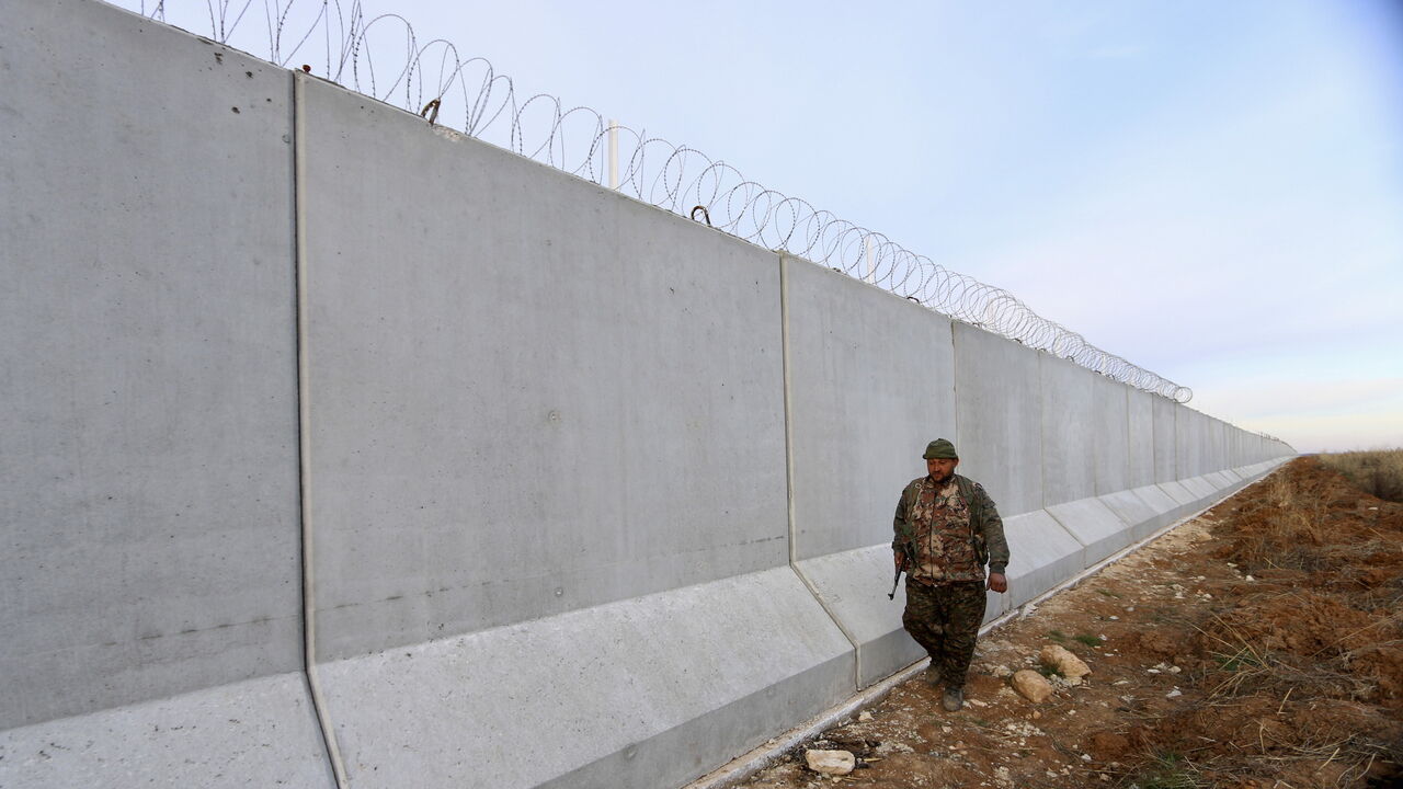 MIDEAST-CRISIS/SYRIA-TURKEY A Kurdish People's Protection Units (YPG) fighter walks near a wall, which activists said was put up by Turkish authorities, on the Syria-Turkish border in the western countryside of Ras al-Ain, Syria January 29, 2016. REUTERS/Rodi Said - GF10000289206