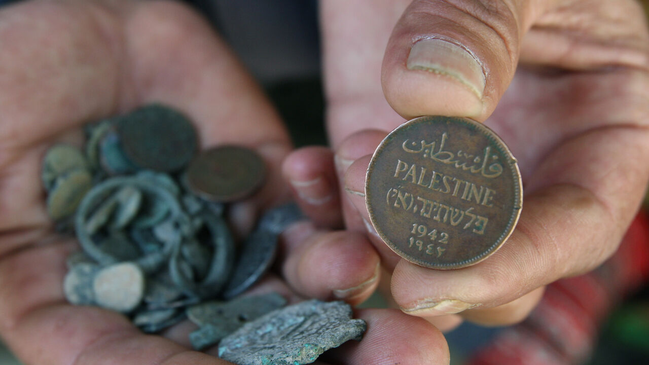 A Palestinian man displays an old Palestinian coin in his shop in the West Bank city of Hebron June 8, 2008. The Palestinian Authority has delayed paying its workers this month after Israel withheld tax funds in anger over Palestinian attempts to block upgraded European Union-Israeli ties, officials said on Sunday. REUTERS/Nayef Hashlamoun (WEST BANK) - GM1E469047K01