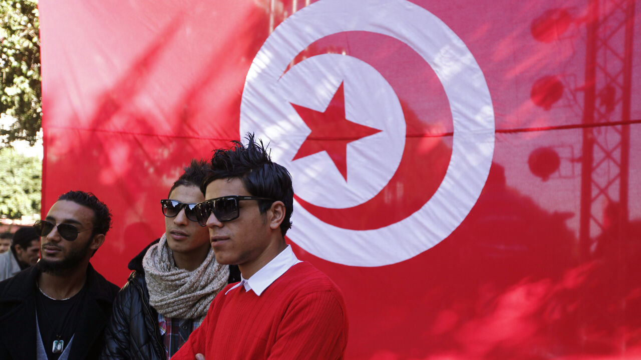 TUNISIA/ Youths pose for a photo in front a Tunisian flag during celebrations of the second anniversary of the Tunisian revolution at Avenue Habib-Bourguiba in Tunis, January 13, 2013. REUTERS/Anis Mili (TUNISIA - Tags: POLITICS CIVIL UNREST ANNIVERSARY) - GM1E91E09KE01